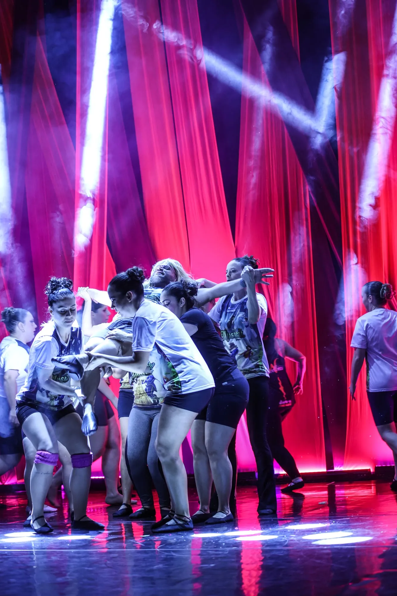 Turma dançando no palco, com luzes coloridas