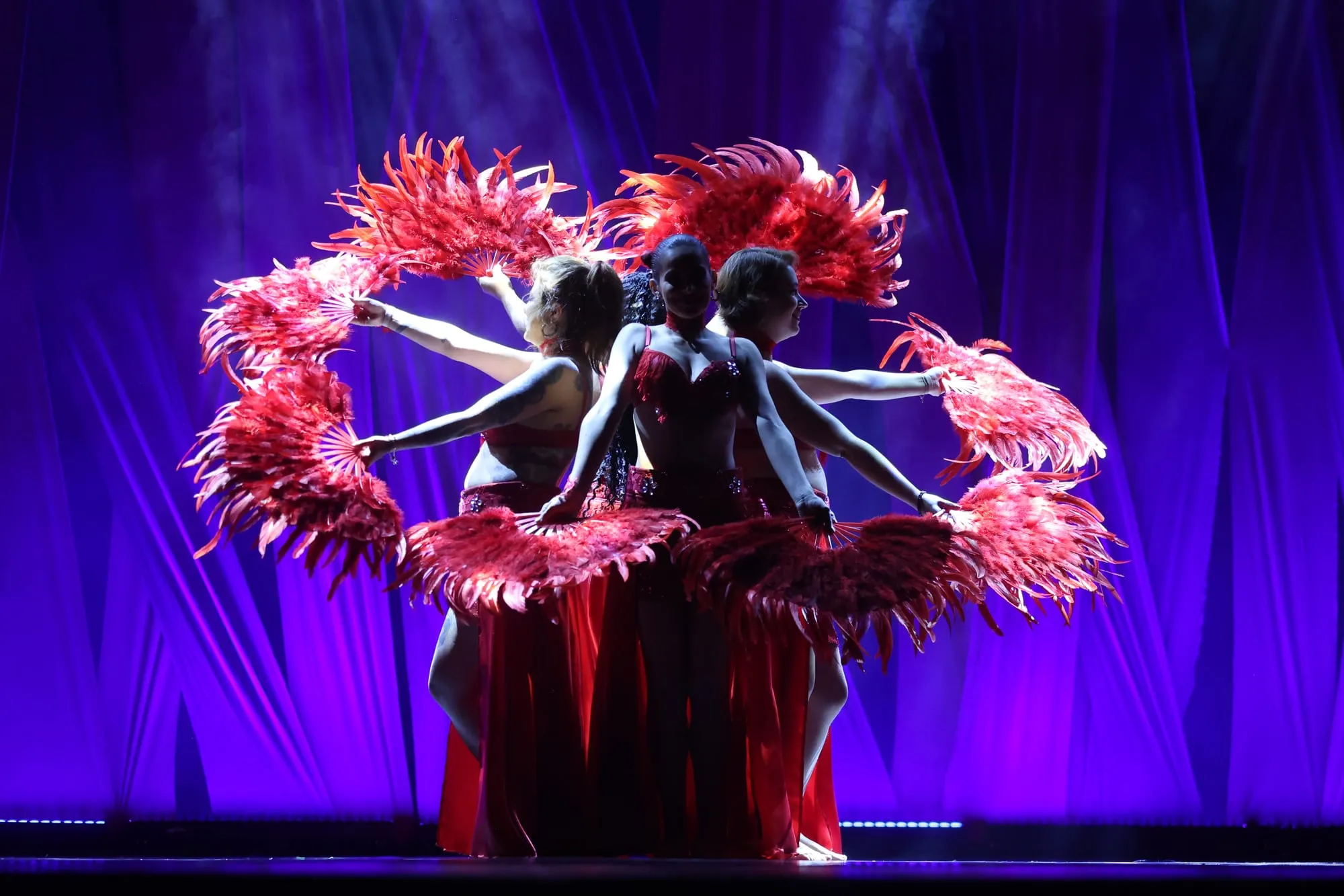 Coreografia com leques sob luz roxa