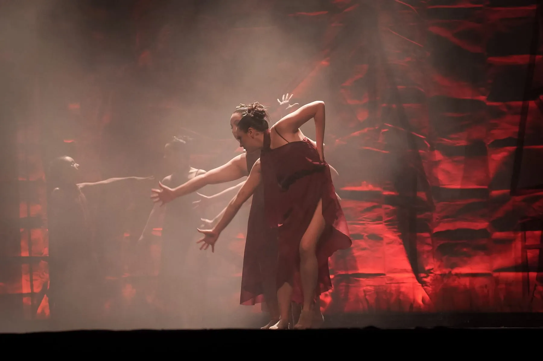 Bailarina em cena com fumaça e luz vermelha