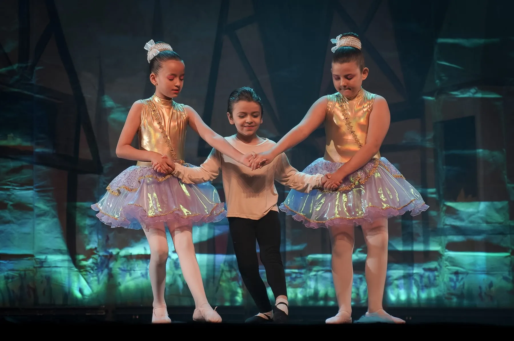 Pequenas bailarinas de mãos dadas no palco