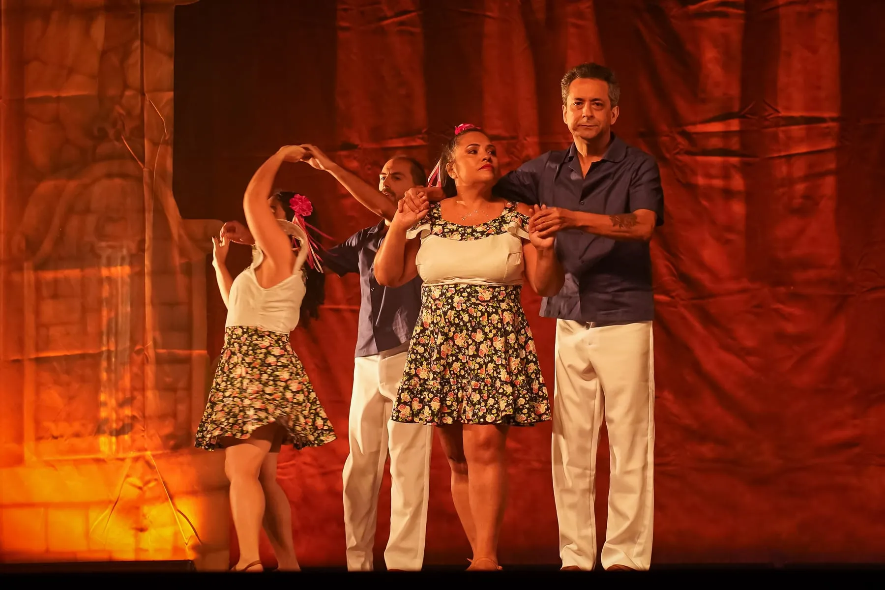 Casal dançando diante de cenário laranja