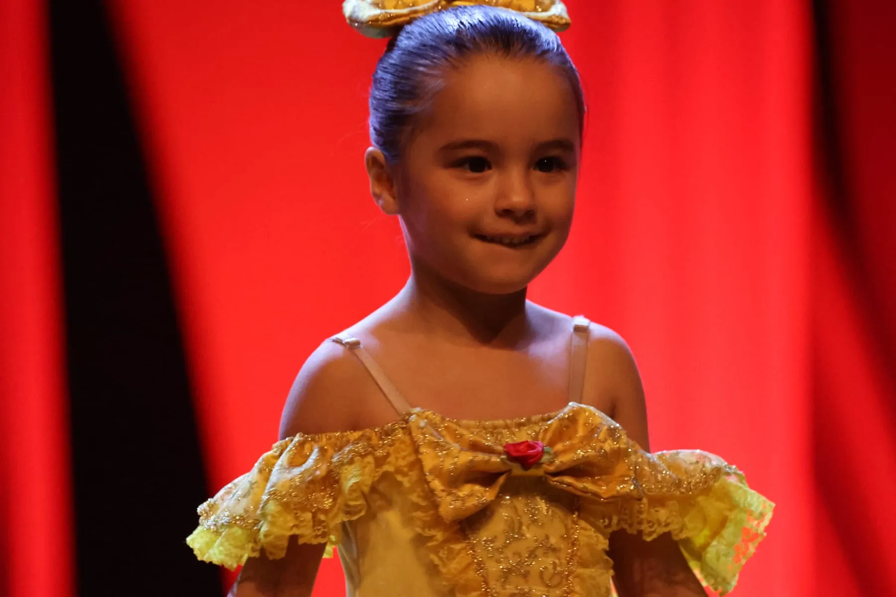 Menina de vestido amarelo sorrindo no palco